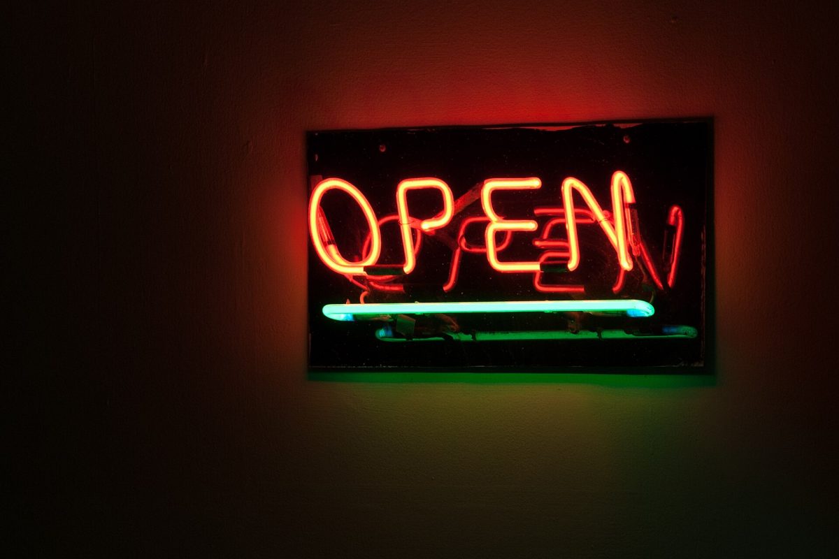 Red neon OPEN sign glowing against a dark storefront interior