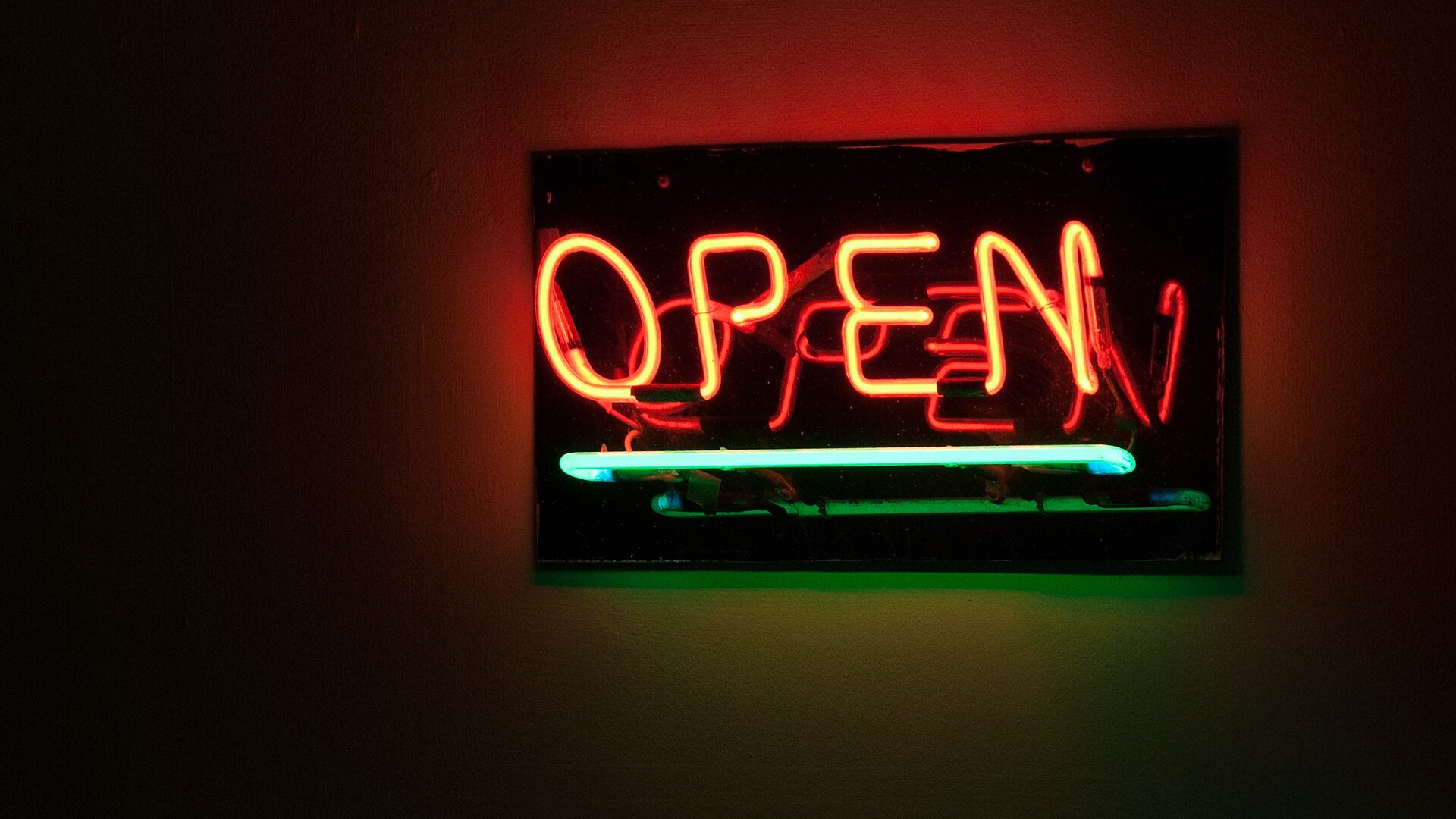 Red neon OPEN sign glowing against a dark storefront interior