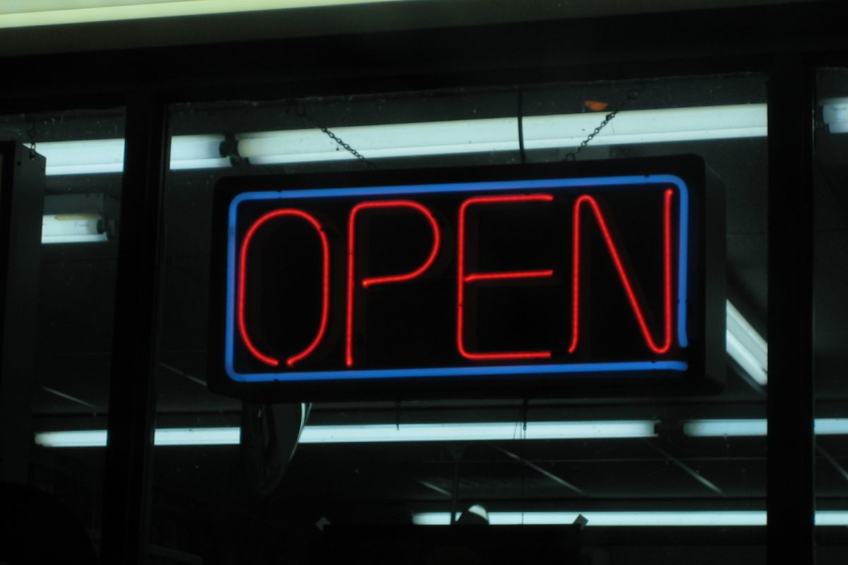 Blue-bordered red neon OPEN sign hanging in a shop window