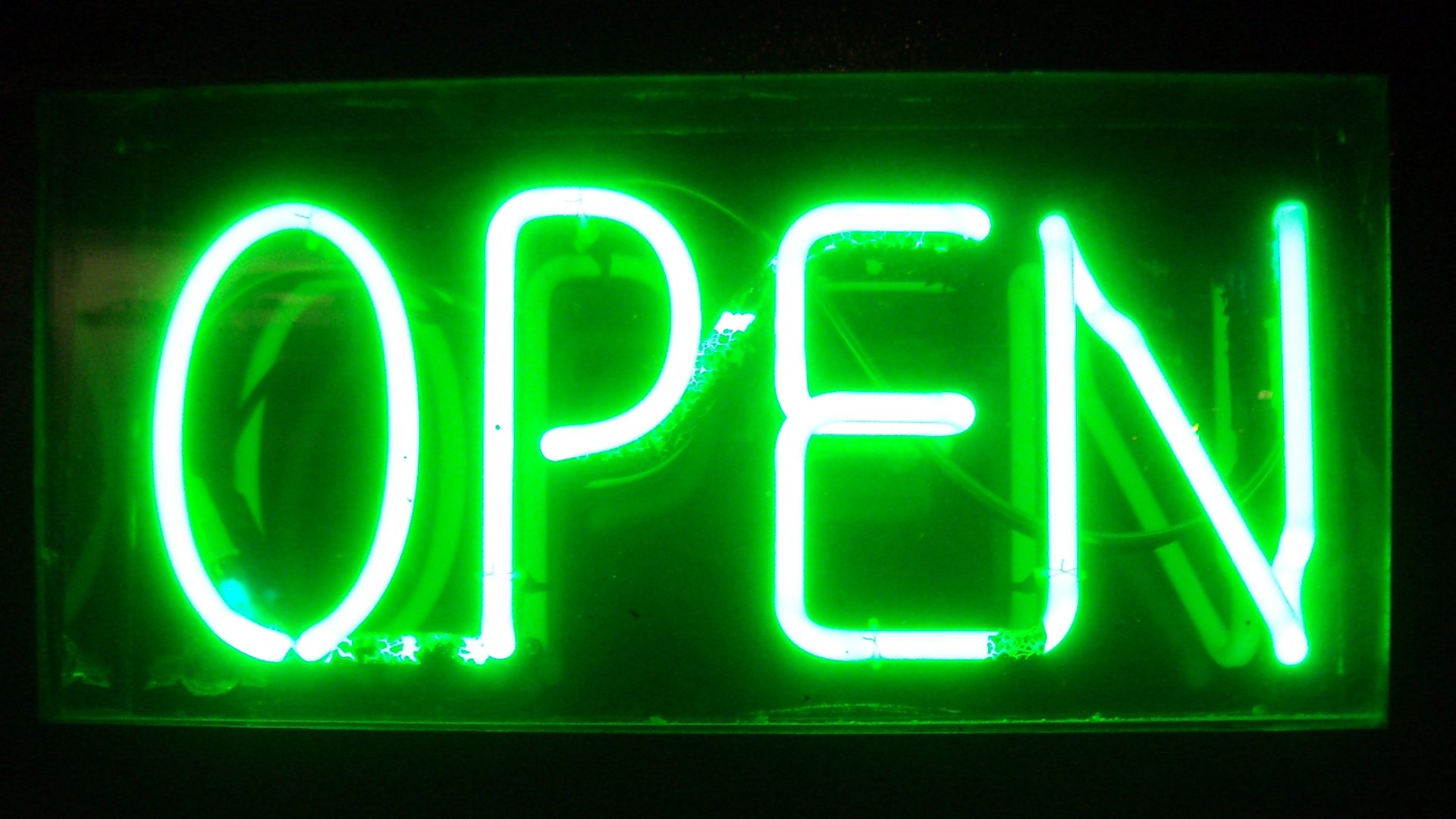 Close-up of a bright green neon block-letter OPEN sign