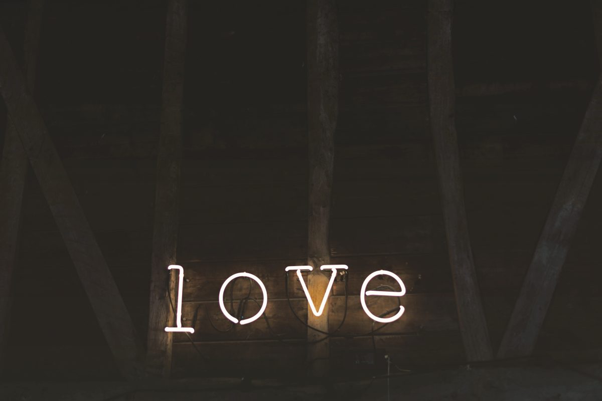 White cursive neon script art piece mounted on reclaimed wood beams