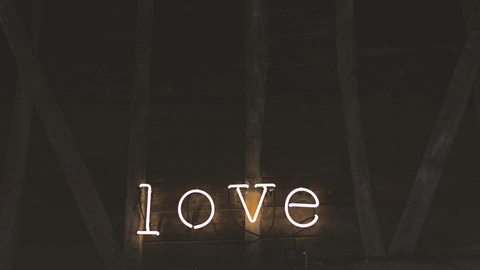 White cursive neon script art piece mounted on reclaimed wood beams