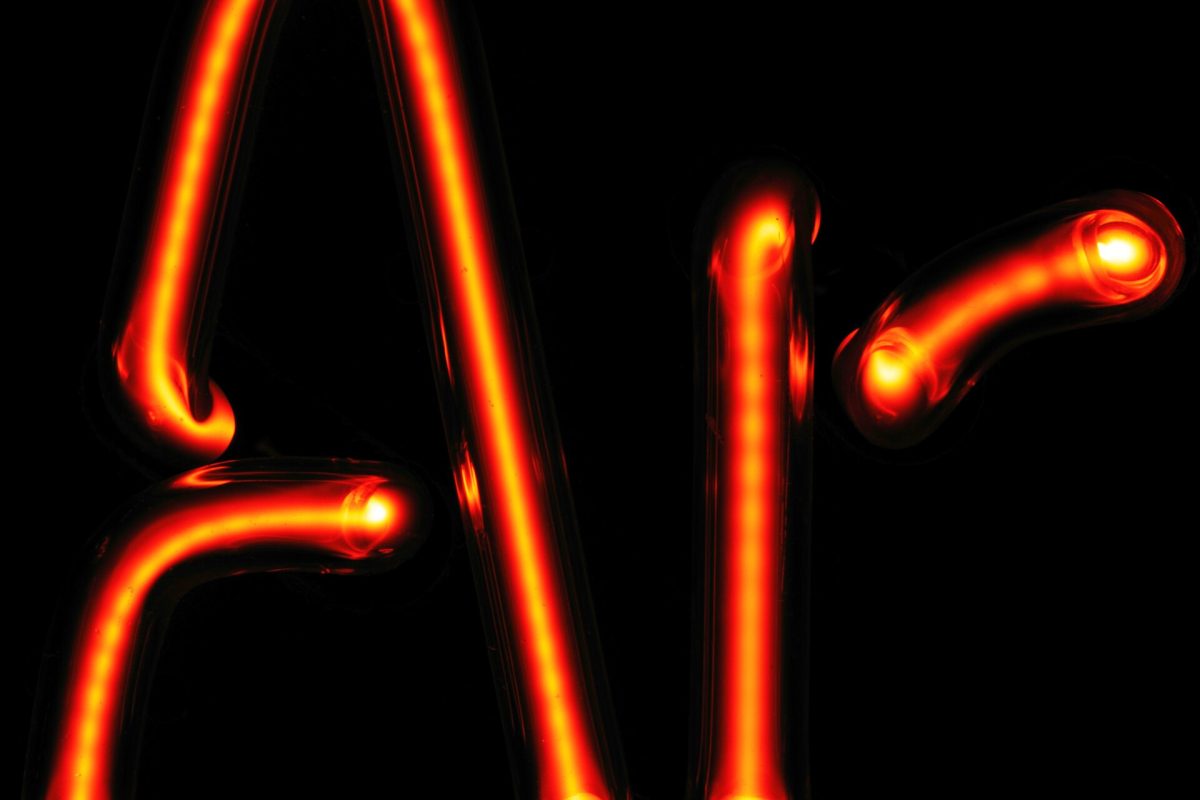 Close-up detail of hand-bent red neon glass tubing and electrode joints