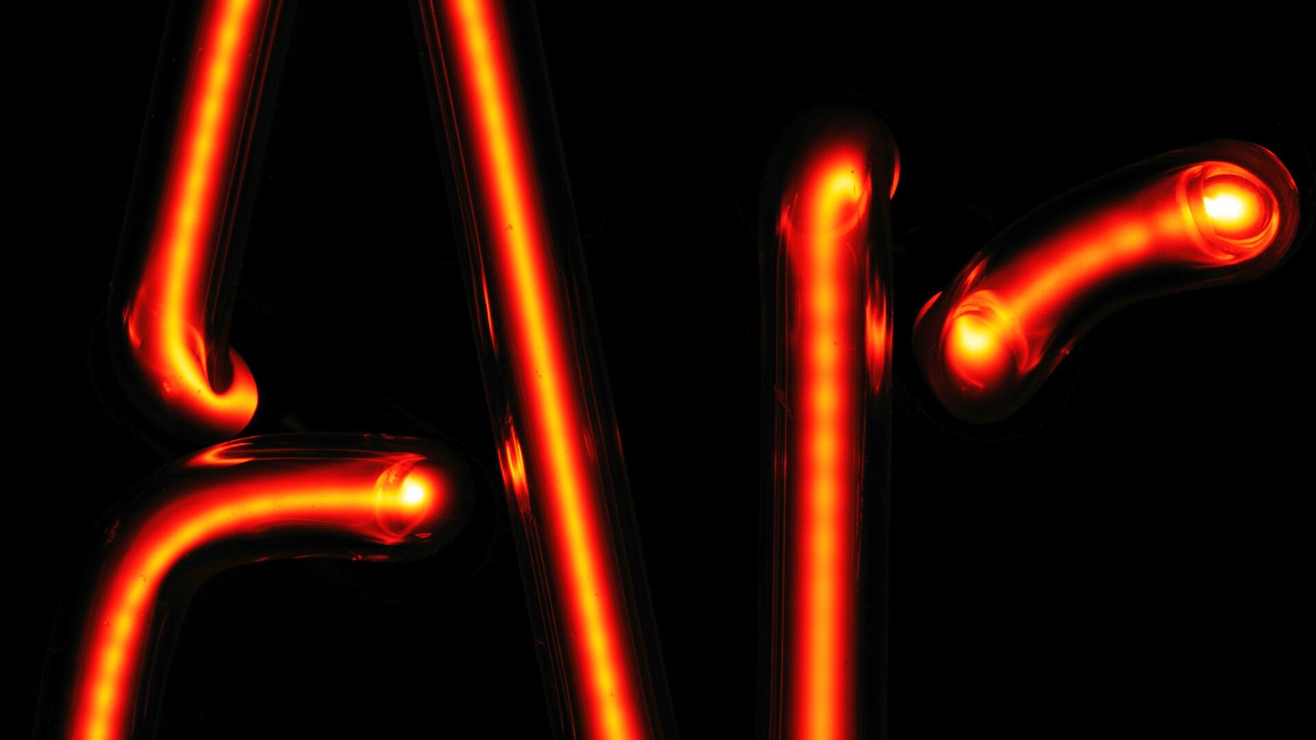 Close-up detail of hand-bent red neon glass tubing and electrode joints